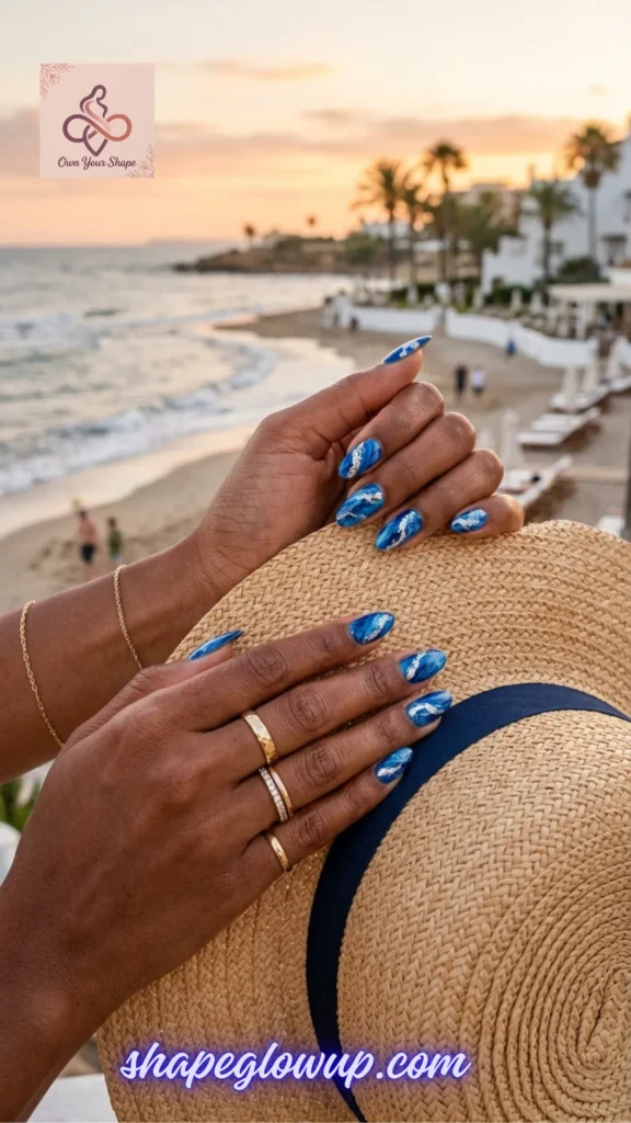 Deep skin tone holding a straw sunhat with metallic silver and blue marble nail art, a stunning look from 10 Stunning 4th of July Nail Arts to Try This Year!