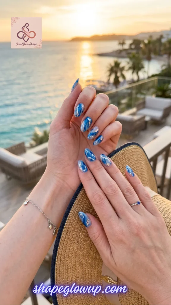 Elegant blue ocean marble manicured hands holding a straw hat overlooking a coastal sunset town, inspired by 10 Stunning 4th of July Nail Arts to Try This Year!