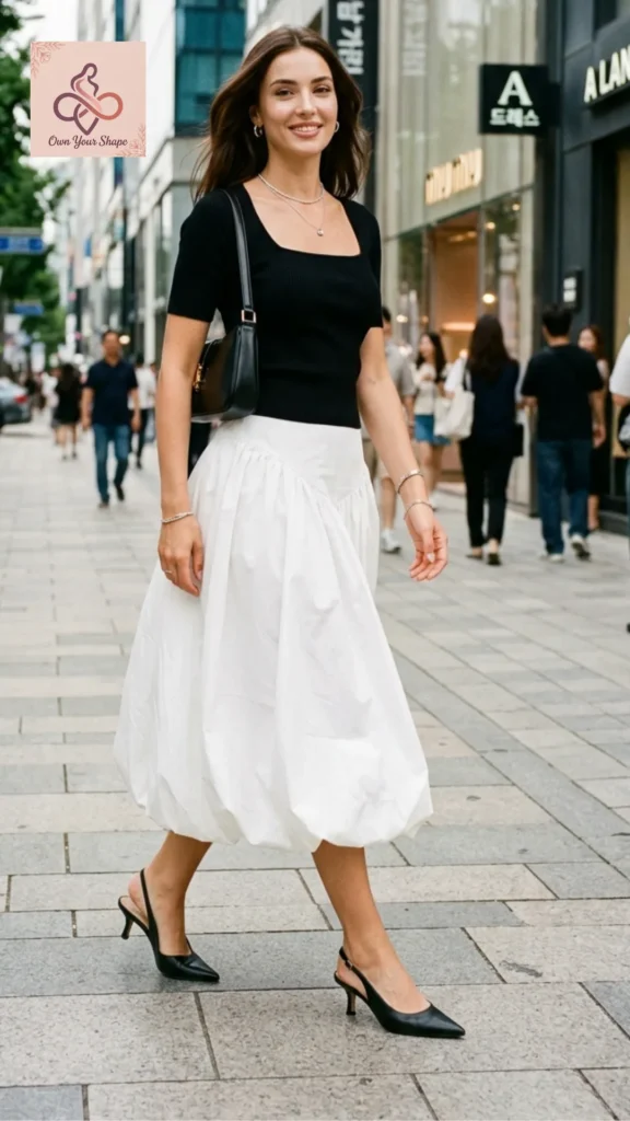 A woman walking down a shopping street in a black square-neck top and white bubble skirt for 2026 Korean Fashion is HERE: 5 Must-Wear Trends You Need to Try.