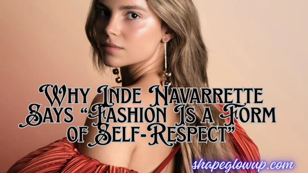 Close-up portrait of actress Inde Navarrette looking over her shoulder against a warm, gradient beige background. She wears long, geometric drop earrings and a textured, pleated rust-red fabric draped over her arm. Overlaid stylized text reads: "Why Inde Navarrette Says 'Fashion Is a Form of Self-Respect'" with the website URL "shapeglowup.com" in the bottom right corner.